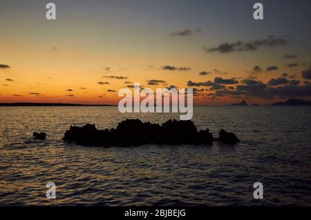 Barca a vela vicino a Caló de s'oli al tramonto, con l'isolotto es Vedrá in lontananza (Parco Naturale di Ses Salines, Formentera, Baleares, Mar Mediterraneo, Spagna) Foto Stock