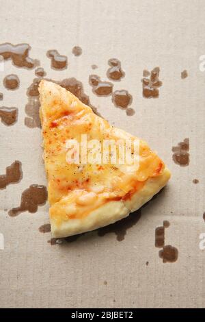 Gustosa fetta di pizza con macchie grasse su cartone Foto Stock