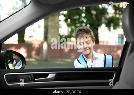 Prendere alunno dopo scuola. Ragazzo vicino all'auto Foto Stock