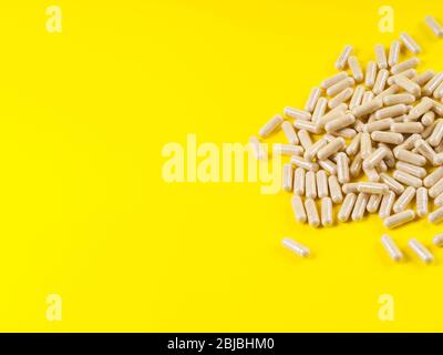 Maca polvere in capsule su sfondo giallo Foto Stock