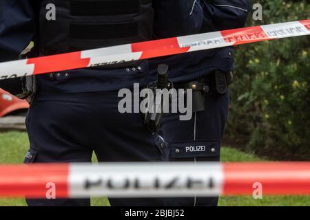 Gelsenkirchen, Germania. 29 aprile 2020. Gli agenti di polizia stanno stando dietro un cordone di polizia sulla scena del crimine. Un poliziotto è stato ucciso questa mattina durante un'operazione SEK a Gelsenkirchen. Quando gli ufficiali stavano per fare una ricerca casa su un sospetto in un'indagine sulla droga, il sospetto si dice che abbia sparato i colpi agli ufficiali SEK. Uno di loro ha colpito il poliziotto SEK. Credit: Bernd Thissen/dpa - ATTENZIONE: I nomi delle campanine sono stati pixelati per motivi legali/dpa/Alamy Live News Foto Stock