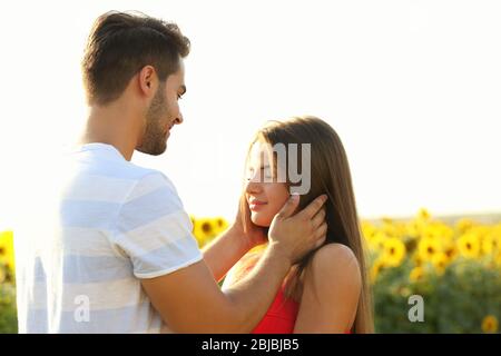 Coppia giovane romantica abbracciata in un campo di girasoli Foto Stock