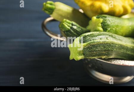 Zucchine fresche in colapasta su fondo di legno blu Foto Stock