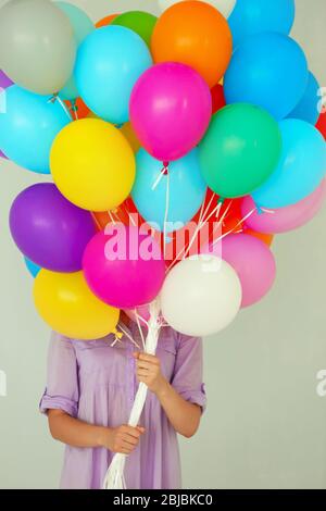 Ragazza che tiene molti palloncini colorati su sfondo parete Foto Stock