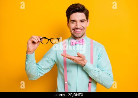 Look nuovo prodotto per la cura degli occhi. Positivo ragazzo allegro tenere presente specifiche per la buona vista indossare abiti eleganti isolato sopra brillante colore brillante Foto Stock