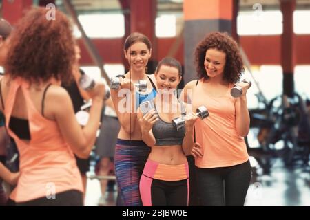 Gruppo di giovani donne sportive che prendono selfie vicino specchio in palestra Foto Stock