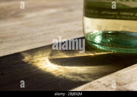 giochi di luci e ombre attraverso raggi solari e una bottiglia di vino bianco Foto Stock