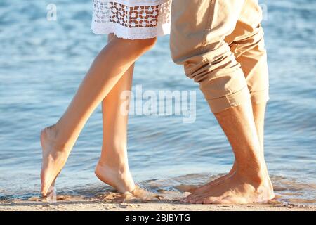 Due paia di gambe in piedi in acqua, primo piano Foto Stock