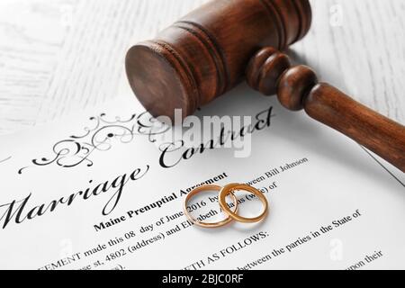 Anelli di nozze d'oro con gavel giudice sul contratto di matrimonio, closeup Foto Stock