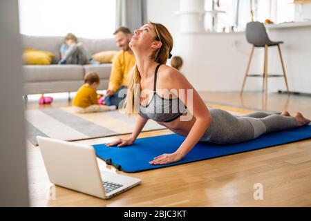 Giovane donna sta esercitando lo yoga a casa. Fitness, allenamento, vita sana e concetto di dieta. Foto Stock