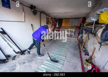 Allenamento ragazzo in hockey home garage tiro range durante Covid-19 quarantena Foto Stock