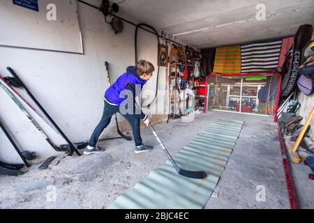 Allenamento ragazzo in hockey home garage tiro range durante Covid-19 quarantena Foto Stock