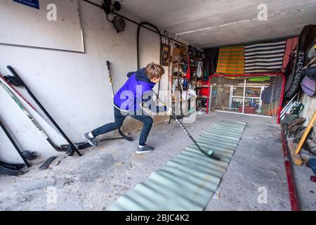 Allenamento ragazzo in hockey home garage tiro range durante Covid-19 quarantena Foto Stock