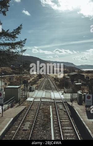 Un passaggio a livello vicino alla stazione ferroviaria di Strathcarron sulla linea Kyle of Lochalsh, che serve il piccolo villaggio di Strathcarron e il villaggio più grande Foto Stock