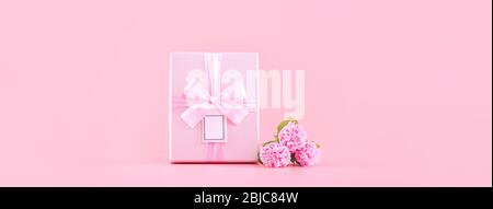 Festa della mamma concetto regalo design, rosa mazzo di fiori di garofano con scatola avvolta, carrello, borsa, isolato su sfondo rosa chiaro, copia Foto Stock