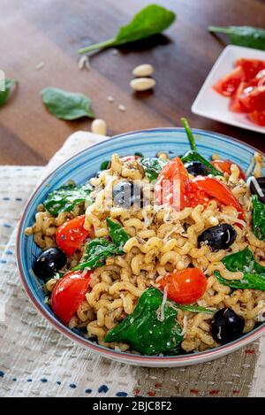 Fusilli lunghi, pomodoro di ciliegia, olive nere e spinaci, cibo mediterraneo per la dieta. Foto Stock