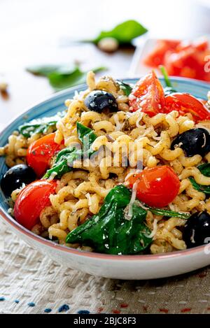 Fusilli lunghi, pomodoro di ciliegia, olive nere e spinaci, cibo mediterraneo per la dieta. Foto Stock