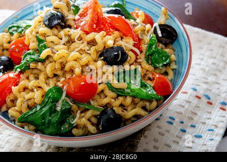 Fusilli lunghi, pomodoro di ciliegia, olive nere e spinaci, cibo mediterraneo per la dieta. Foto Stock