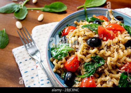 Fusilli lunghi, pomodoro di ciliegia, olive nere e spinaci, cibo mediterraneo per la dieta. Foto Stock