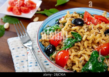 Fusilli lunghi, pomodoro di ciliegia, olive nere e spinaci, cibo mediterraneo per la dieta. Foto Stock