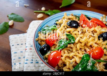 Fusilli lunghi, pomodoro di ciliegia, olive nere e spinaci, cibo mediterraneo per la dieta. Foto Stock