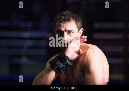 Sport: Il kickboxer dell'uomo sta esercitandosi nel calcio in una palestra di boxe Foto Stock