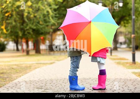 Bambini nascosti dietro ombrello colorato nel parco Foto Stock