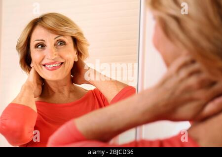 Donna anziana felice che guarda in specchio Foto Stock