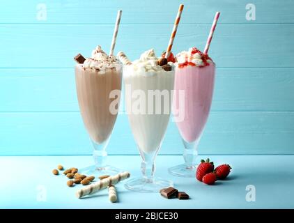 Deliziosi milkshake su sfondo di legno blu Foto Stock