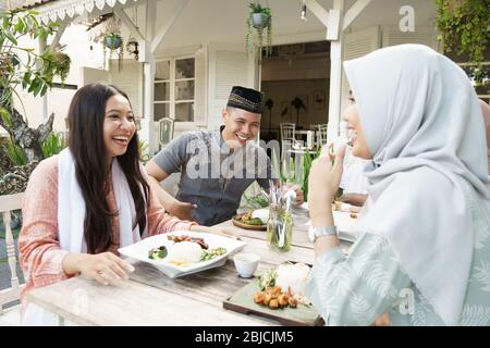 i musulmani rompono il digiuno insieme. amici e famiglia seduti insieme gustare la cena iftar Foto Stock