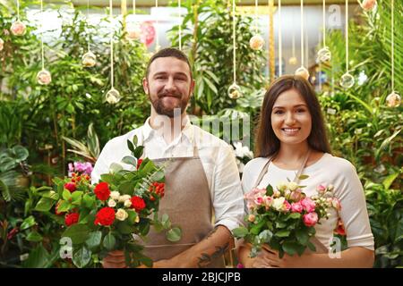 Fioristi maschi e femmine con bouquet belli in serra Foto Stock