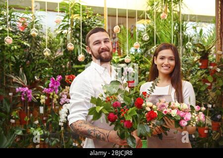 Fioristi maschi e femmine con bouquet belli in serra Foto Stock