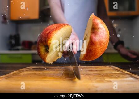 Chef che taglia a metà una mela gialla matura con un grosso coltello in  movimento. Spruzzi di acqua e succo volare in diverse direzioni e congelare  in aria Foto stock - Alamy