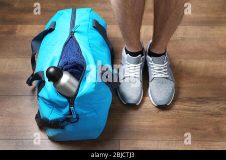 Donna in piedi vicino a borsa sportiva con bottiglia, primo piano Foto Stock