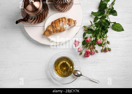 Gustosa colazione con una tazza di tè e croissant freschi su tavolo bianco Foto Stock