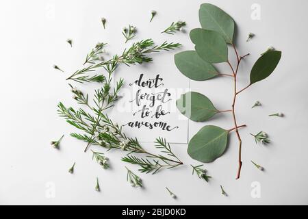 Citazione 'non dimenticate di essere impressionante' scritto su carta con foglie e fiori su sfondo bianco. Vista dall'alto Foto Stock