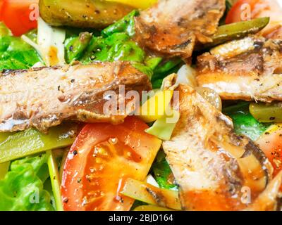 Insalata condita con pomodori lattuga in scatola, peperoni gialli, cetriolini e cipolle tagliati a fette Foto Stock