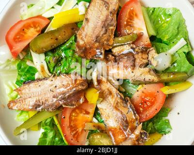 Ciotola di insalata condita con pomodori lattuga in scatola, peperoni gialli, cetriolini e cipolle a fette Foto Stock