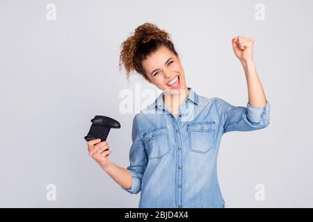 Foto di bella bella signora folle tenendo joystick dipendente gamer buon umore gioire meglio vincere sollevare pugno indossare casual denim blu camicia isolato grigio Foto Stock