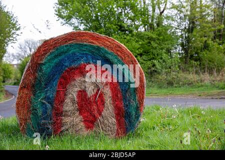 Caerphilly, Galles, Regno Unito. 29 aprile 2020. Un arcobaleno e cuore è dipinto in una balla di fieno sulla strada vicino al monte Caerphilly durante la sesta settimana di blocco coronavirus, davanti al clap settimanale per gli accompagnatori. Credit: Mark Hawkins/Alamy Live News Foto Stock