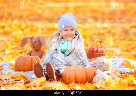 Bambina carina con zucche nel parco autunnale Foto Stock