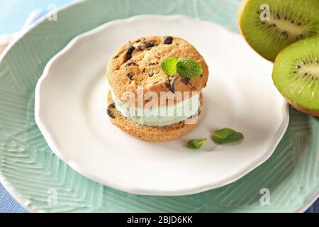 Piatto con delizioso panino di biscotti al gelato e kiwi, primo piano Foto Stock