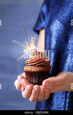 Donna che mantiene una gustosa tortina con sparkler, close up Foto Stock