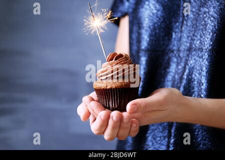 Donna che mantiene una gustosa tortina con sparkler, close up Foto Stock