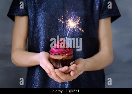 Donna che mantiene una gustosa tortina con sparkler, close up Foto Stock