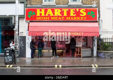 Peckham, Regno Unito. 29 aprile 2020. Vita a Londra del Sud durante il blocco di Coronavirus. La gente si accoda fuori dal mercato irlandese della carne di Harte a Peckham. ( Credit: Sam Mellish/Alamy Live News ) Foto Stock