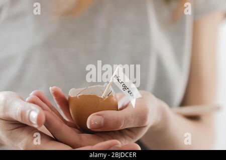le mani della ragazza della donna tengono le uova cute con i semi del micro verde della pianta Foto Stock