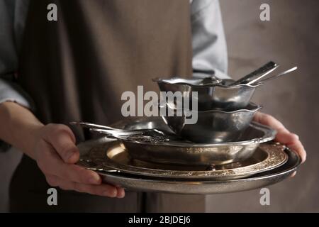 Primo piano di donna che tiene vassoio con stoviglie argento Foto Stock