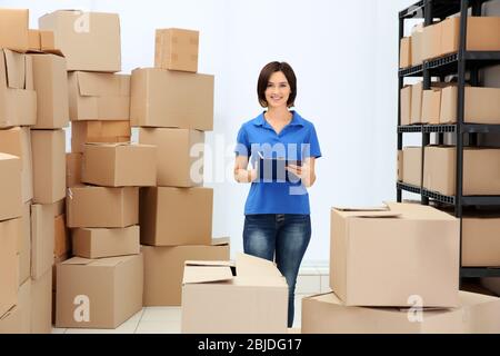 Giovane donna con appunti al magazzino della logistica aziendale Foto Stock