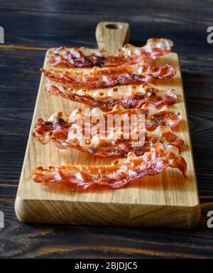 Strisce di pancetta fritte sul legno Foto Stock